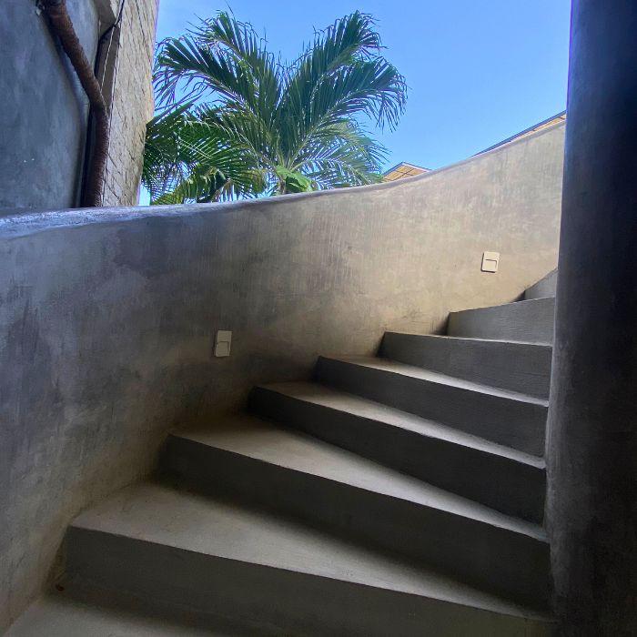 stone spiral staircase in Tulum with palm tree in background.
