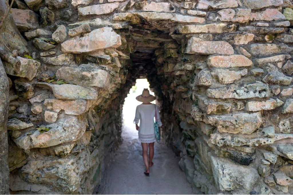 A person walking through a stone arch. 